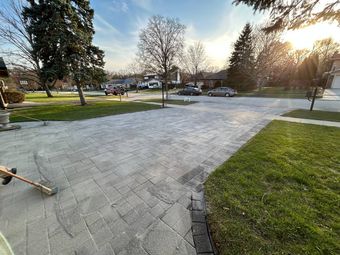Picture of a person using tools to sand pavers on a driveway in Lake Zurich. 