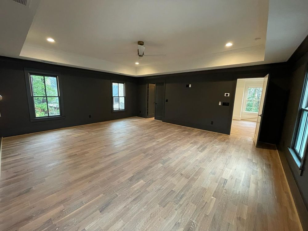 A large empty room with hardwood floors and black walls.