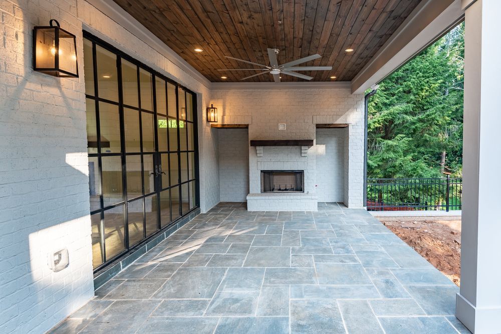 A large patio with a fireplace and a ceiling fan.