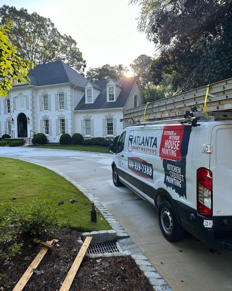 A white van is parked in front of a large white house.