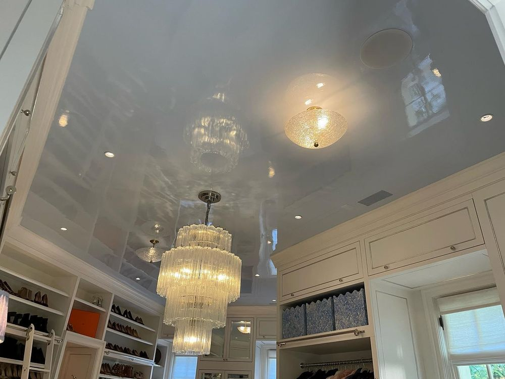 A walk in closet with a shiny ceiling and a chandelier hanging from it.