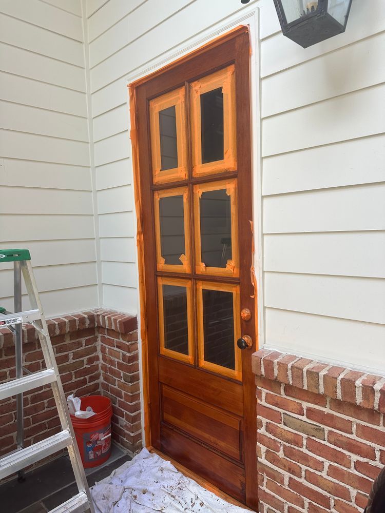 A door is being painted on the side of a house.