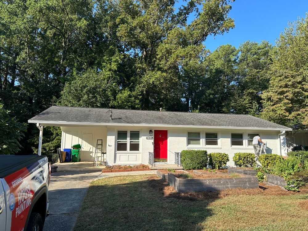 A white house with a red door and a truck parked in front of it.
