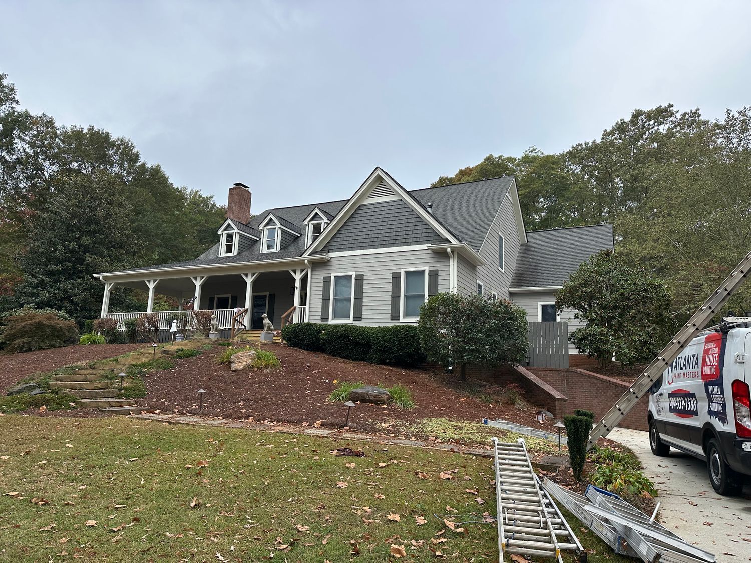 A white house with a black roof and a van parked in front of it.
