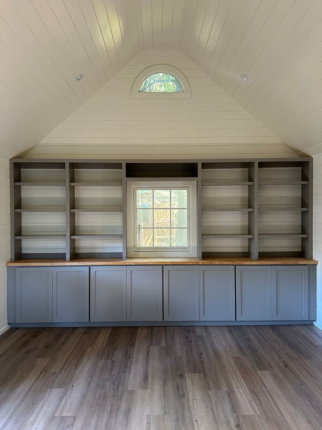 A room with a lot of shelves and a window.