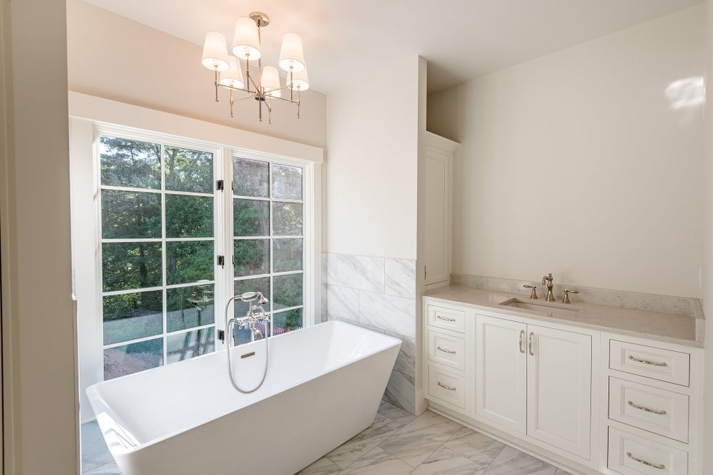 A bathroom with a tub , sink , and window.