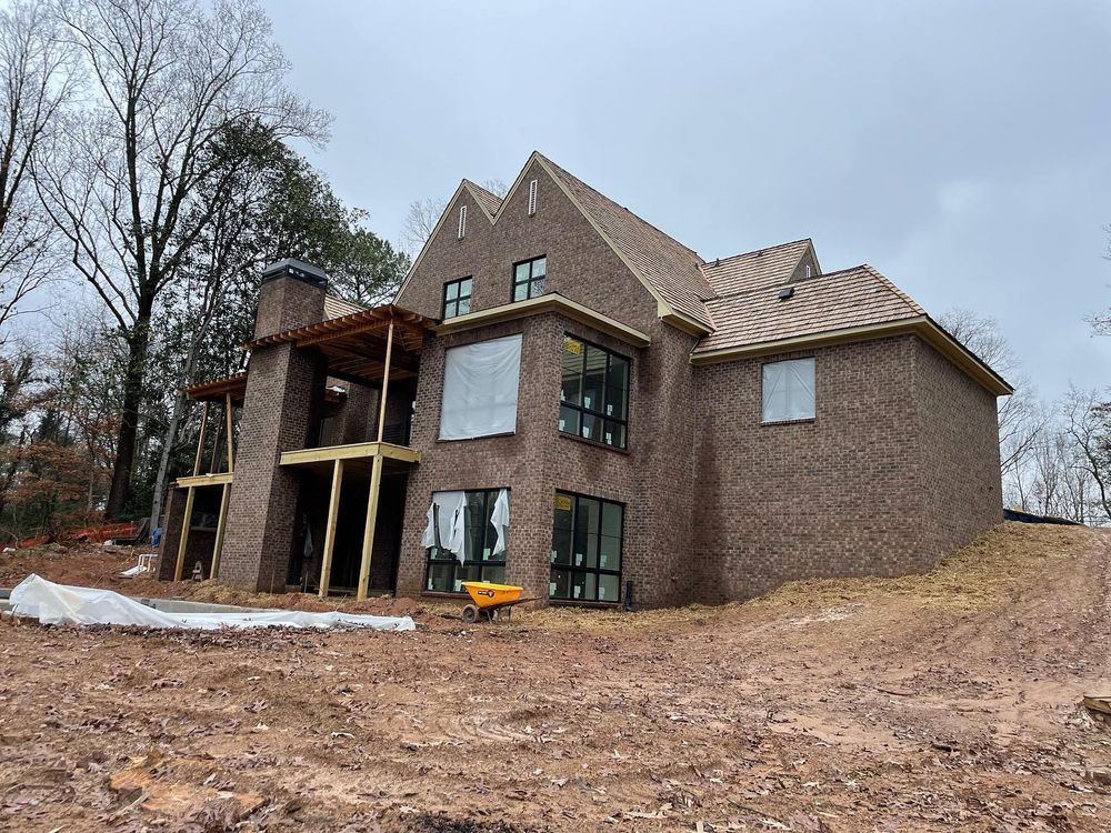 A large brick house is being built on top of a dirt hill.