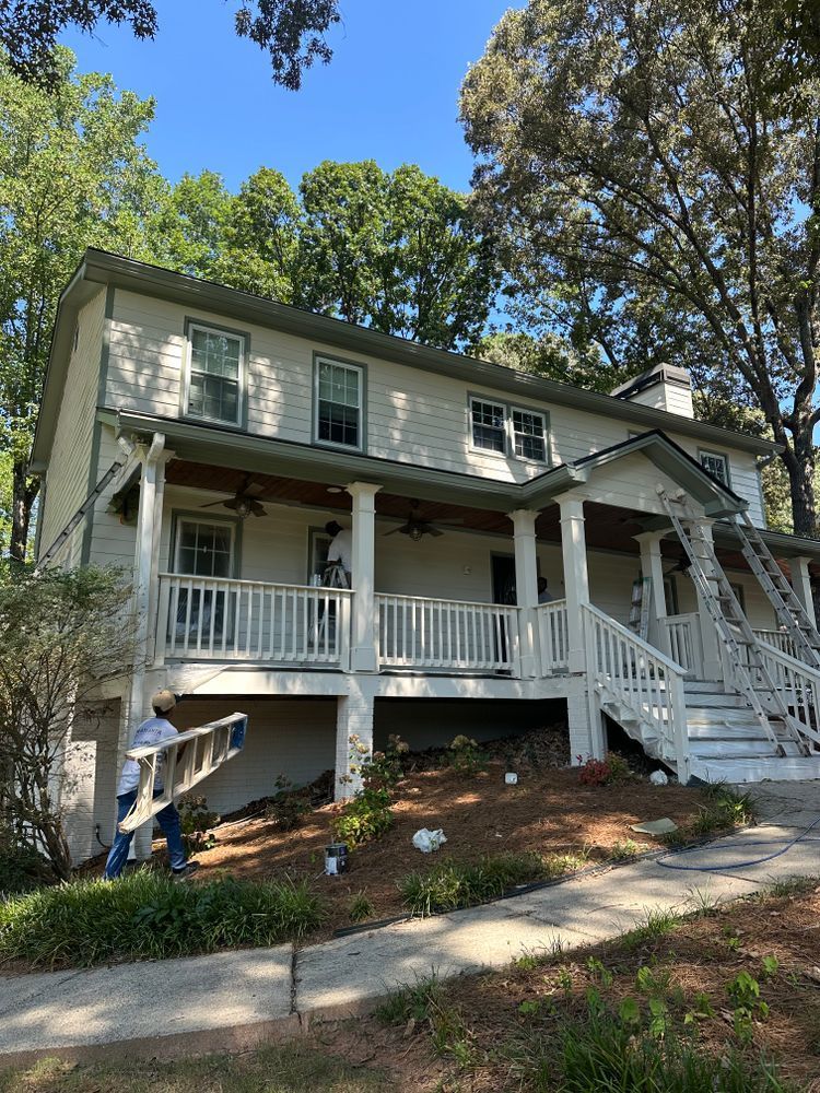 A white house with a porch and stairs is being painted.