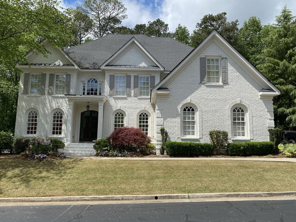 A large white brick house with a black door and shutters