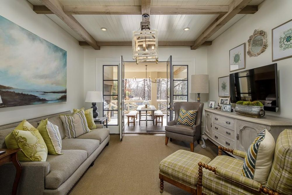 A living room with a couch , chairs , ottoman and television.
