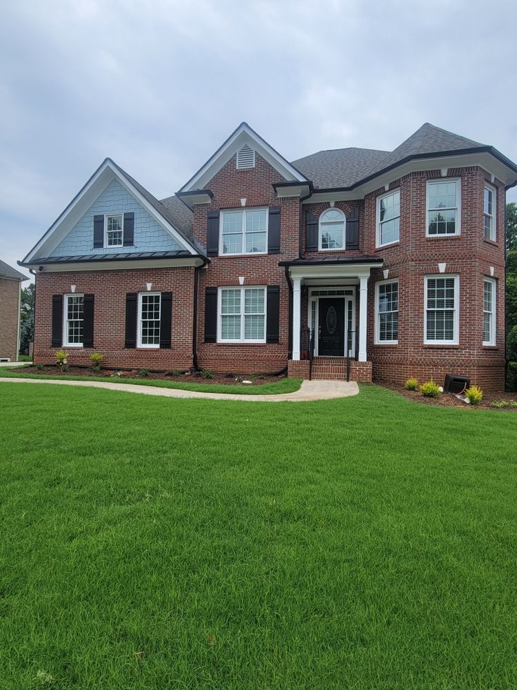 A large brick house with a lush green lawn in front of it.