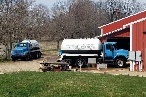 Two Trucks are Parked on a Barn — Marcellus, MI — Richmond Sanitary Service Inc 