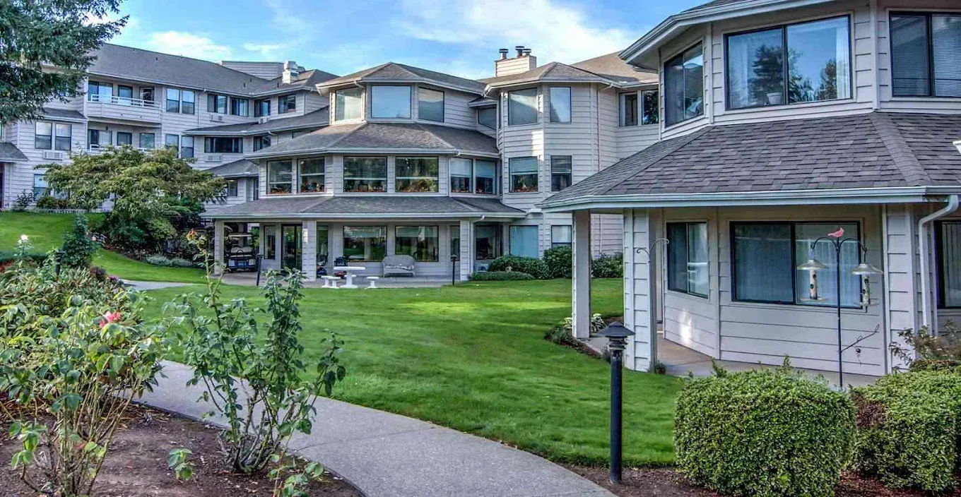 Two people are shaking hands over a model house on a table.