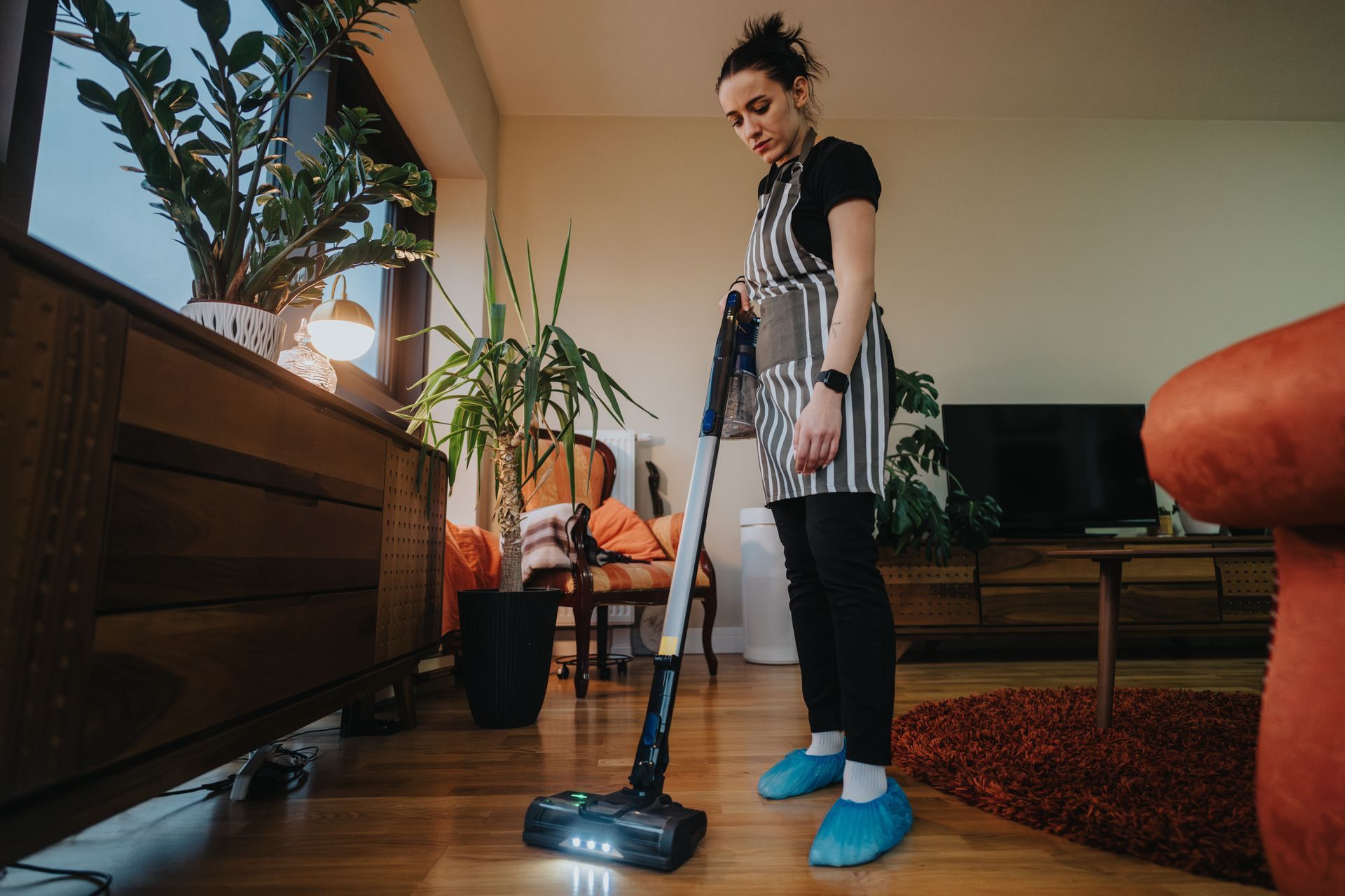 A woman is vacuuming the floor in a living room.