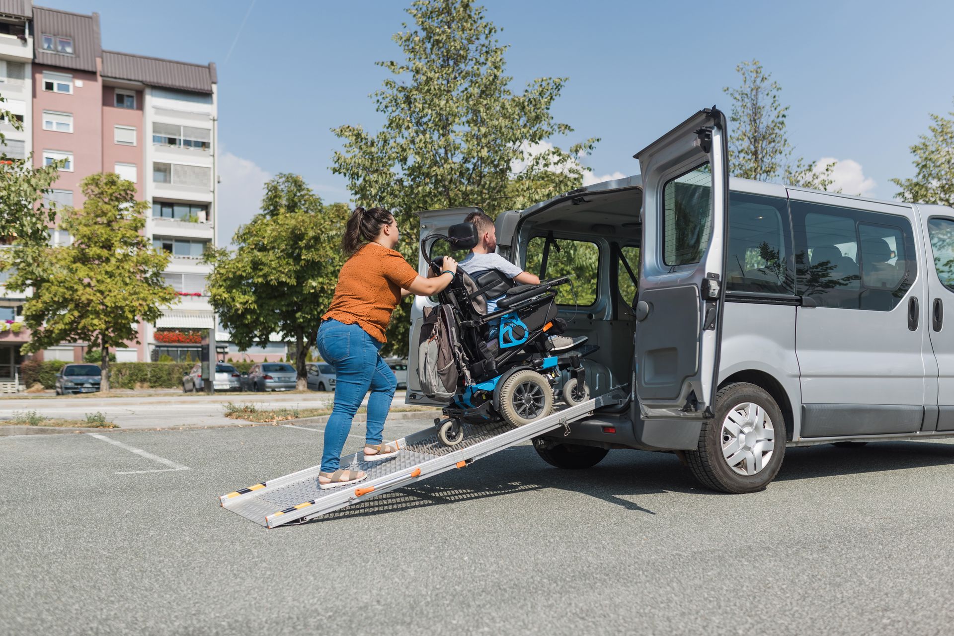 A woman is helping a man in a wheelchair into a van.