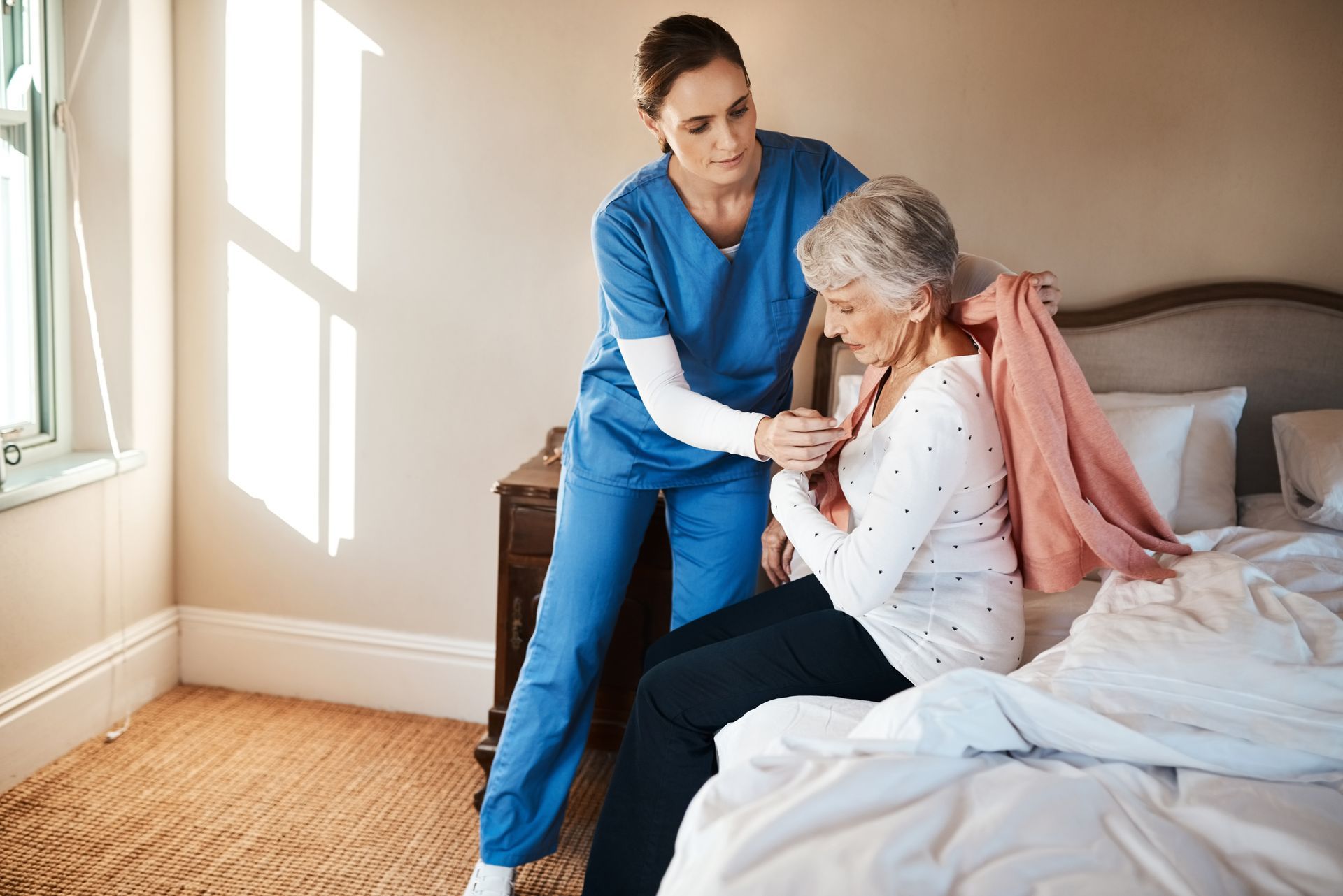 A nurse is helping an elderly woman get out of bed.