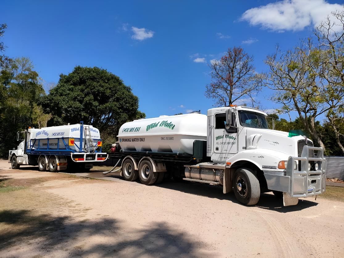 Two Tanker Trucks Are Parked Next to Each Other on a Dirt Road — Wild Water Delivery in Montville, QLD