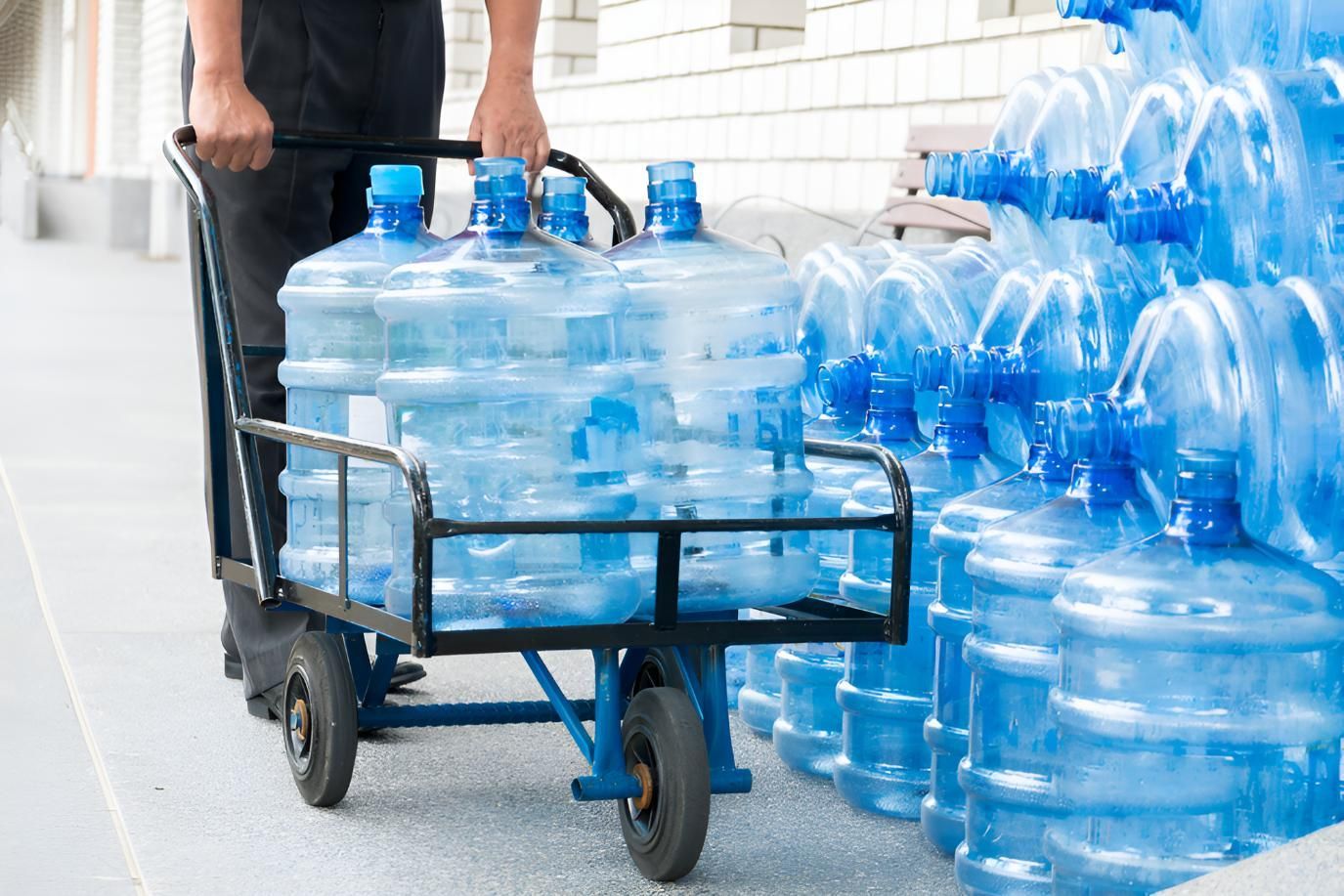 A Man is Pushing a Cart Filled With Water Bottles — Wild Water Delivery in Beerwah, QLD