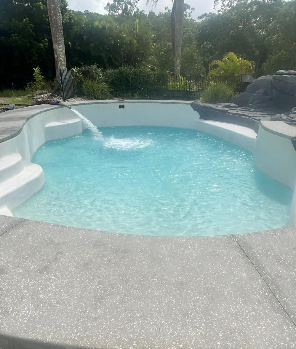 Swimming Pool With Blue Water and White Steps Surrounded by Trees — Wild Water Delivery in Maleny, QLD