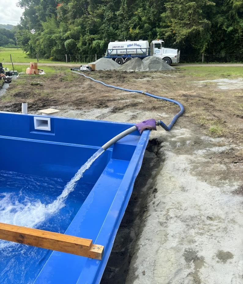 A Blue Swimming Pool With a Hose Attached to It — Wild Water Delivery in Beerwah, QLD