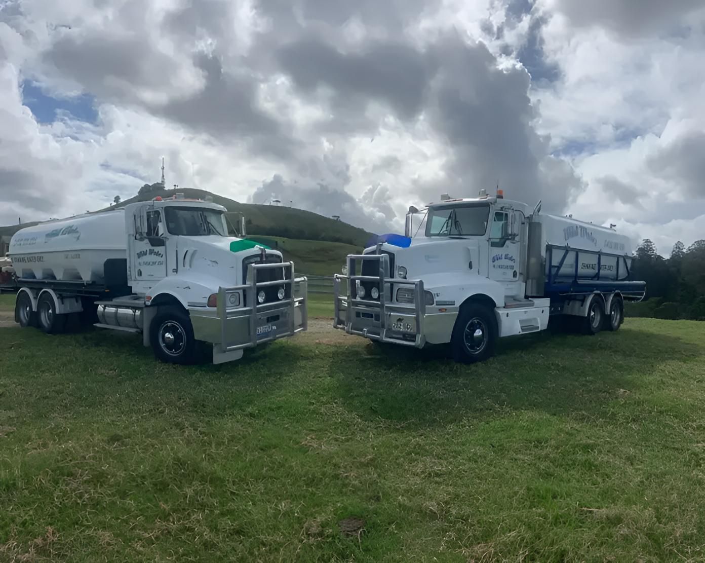 Two Trucks Are Parked Next to Each Other in a Grassy Field — Wild Water Delivery in Peachester, QLD