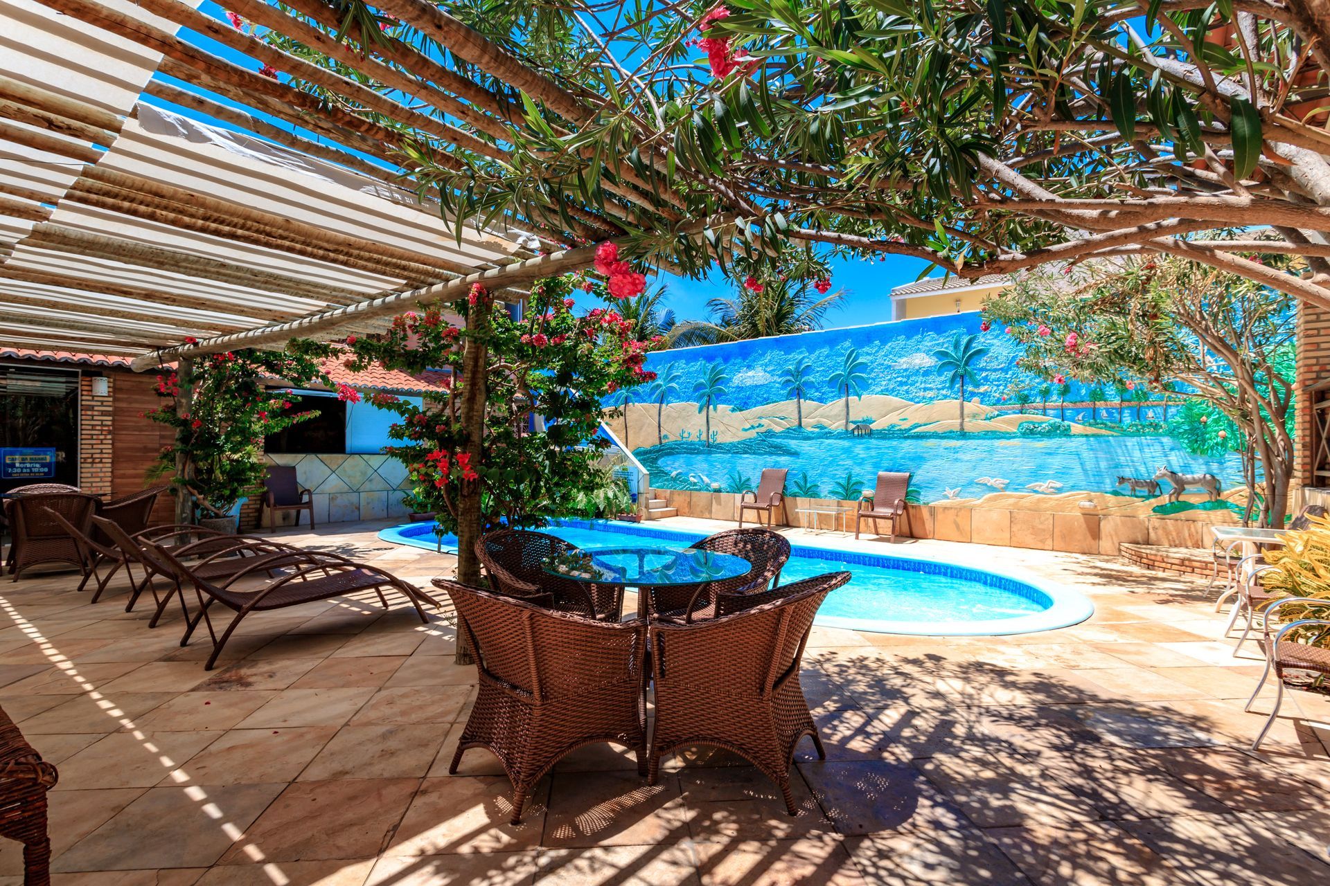 Há uma piscina com mesa e cadeiras em frente.