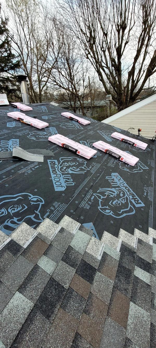A roof with a lot of shingles on it and trees in the background.