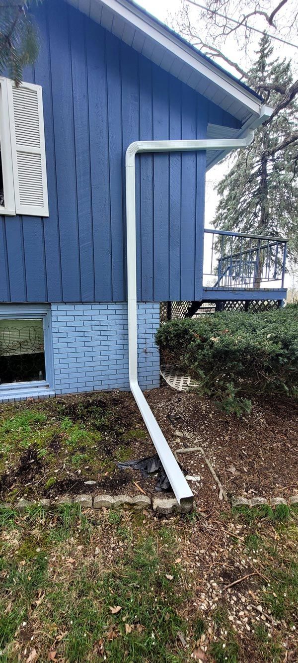 A blue house with a white gutter on the side of it.