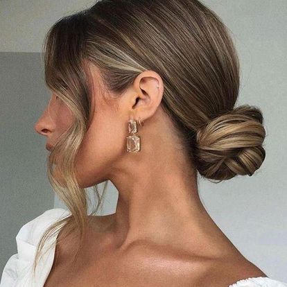 A Woman is Wearing a Bun and Earrings — Experienced Hair Stylist in Gosford, NSW