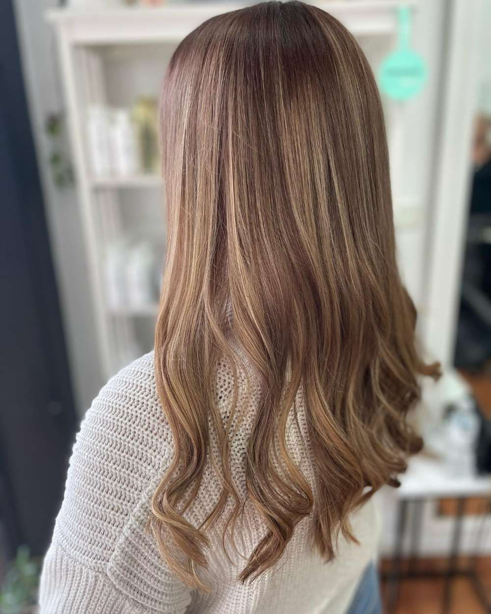 A Woman With Long Brown Hair is Wearing a White Sweater — Innovative Hair Salon in Gosford, NSW