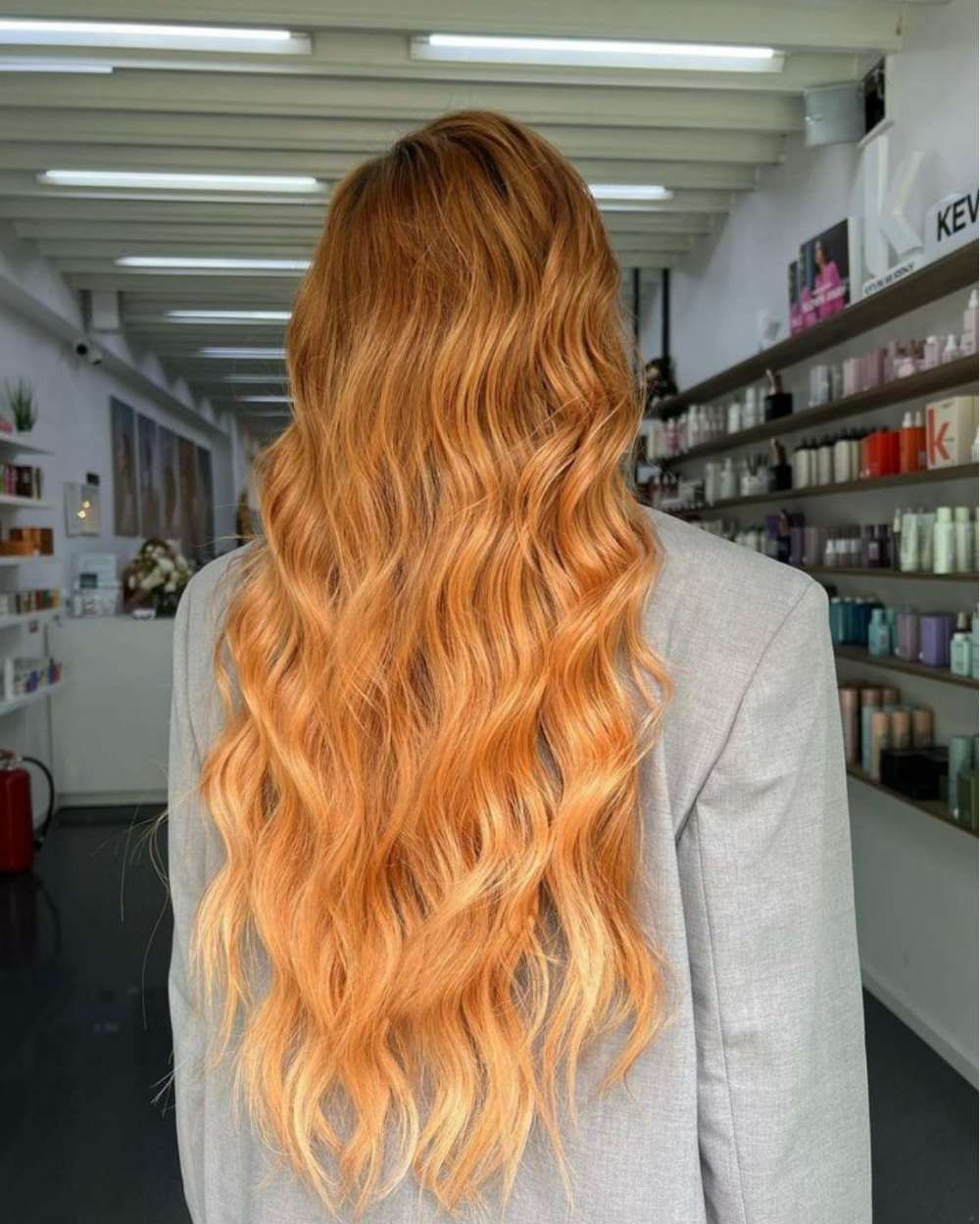 A Woman With Long Red Hair is Standing in a Salon — Innovative Hair Salon in Gosford, NSW