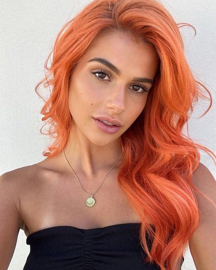 A Woman With Bright Orange Hair is Wearing a Gold Necklace — Expert Colourist in Gosford, NSW