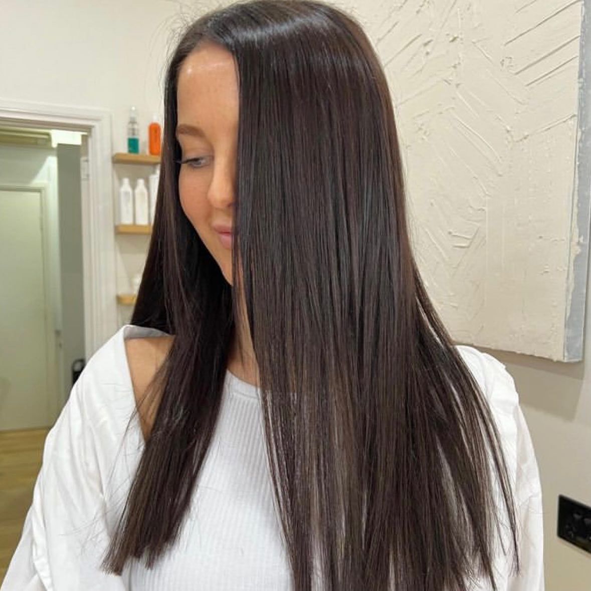 A Woman With Long Dark Hair is Wearing a White Shirt — Innovative Hair Salon in Gosford, NSW