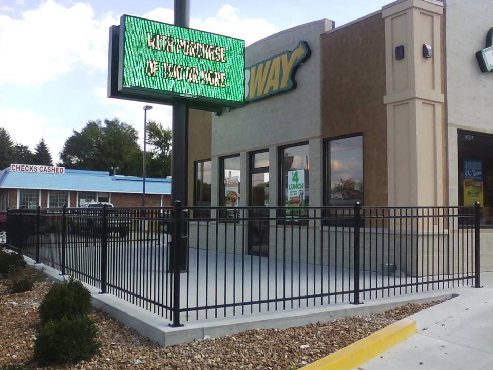 A subway restaurant with a fence in front of it