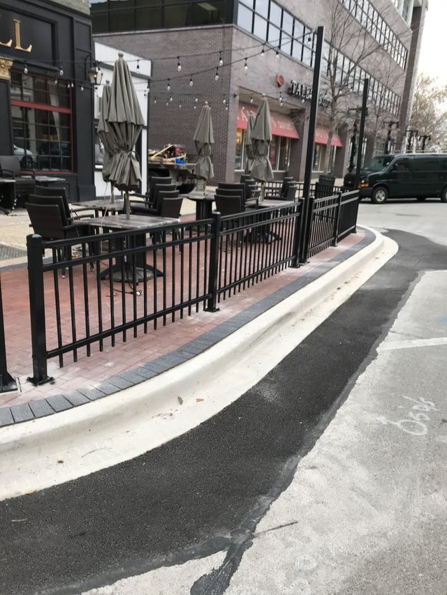 A black fence surrounds a patio with tables and chairs