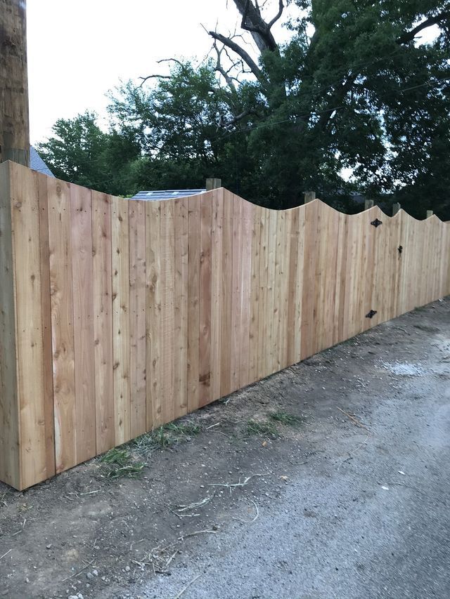 A wooden fence is sitting on the side of a dirt road.
