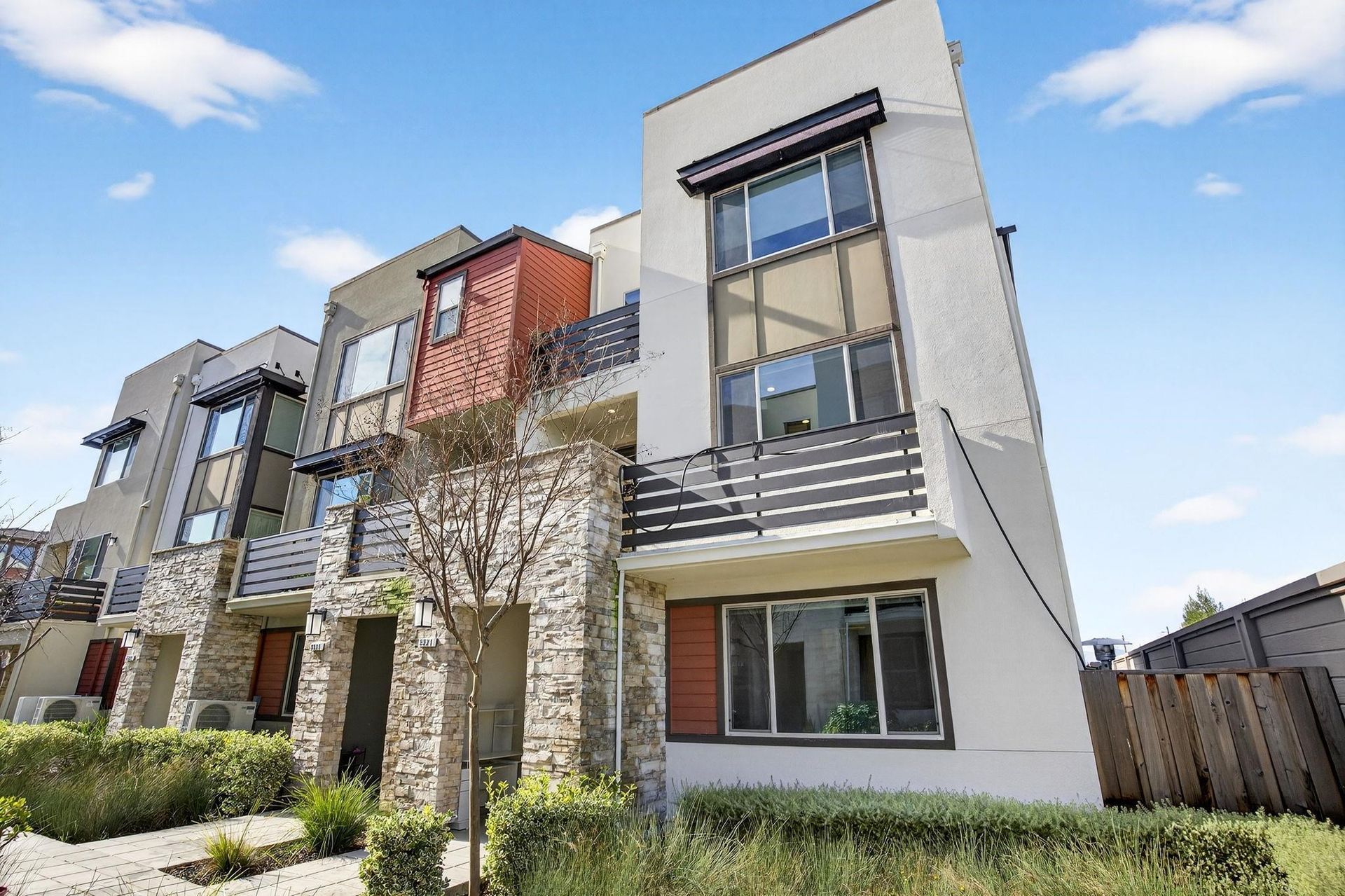 Modern multi-story townhouses with balconies, neutral tones, and stone accents.
