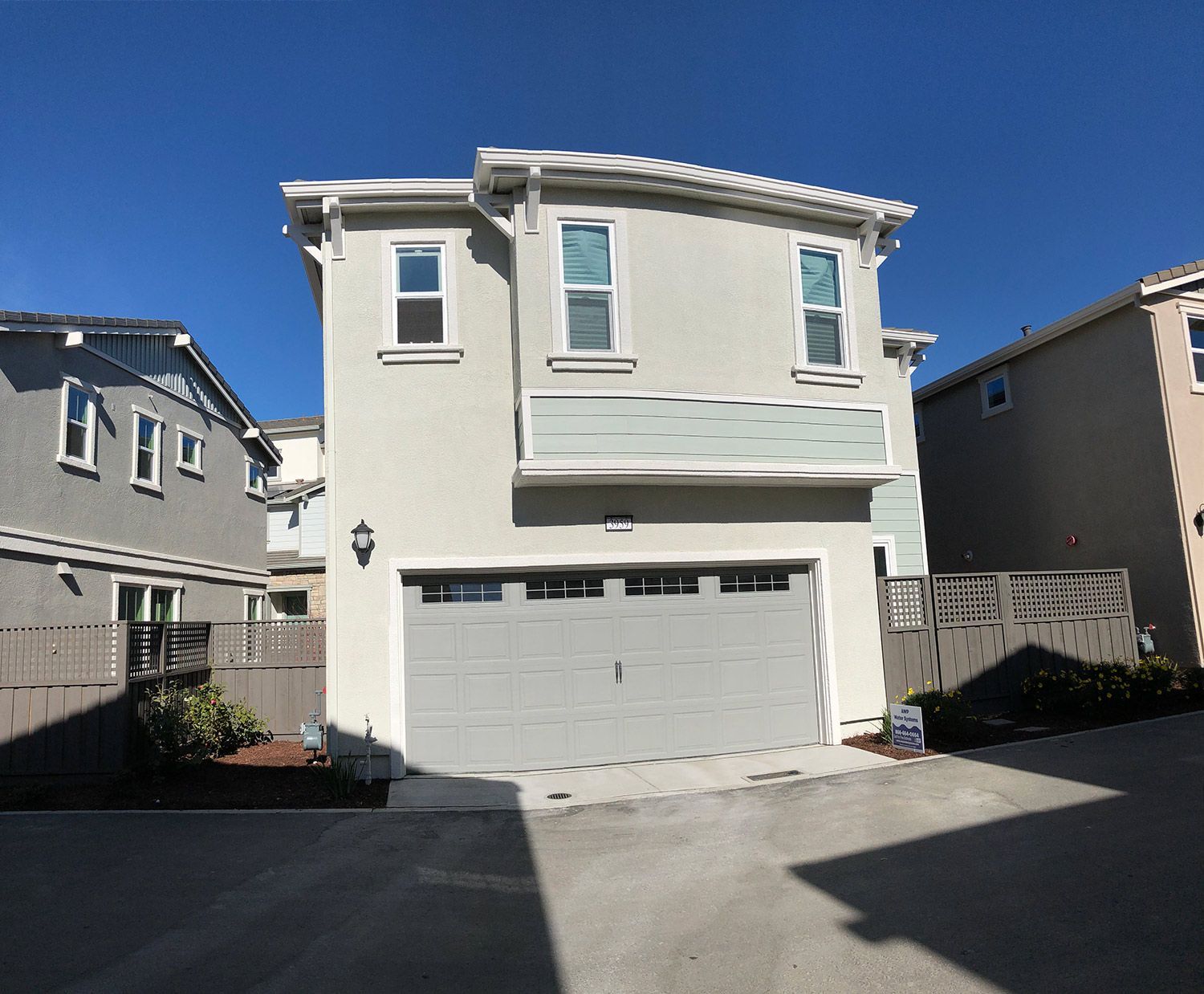 Two-story house with gray garage door, light gray stucco, and blue sky.