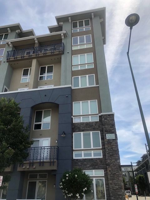 Multi-story apartment building, gray and beige exterior, with balconies and a street lamp.