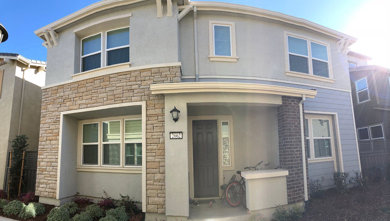 Two-story house with stone and stucco facade, arched windows, and a front porch.