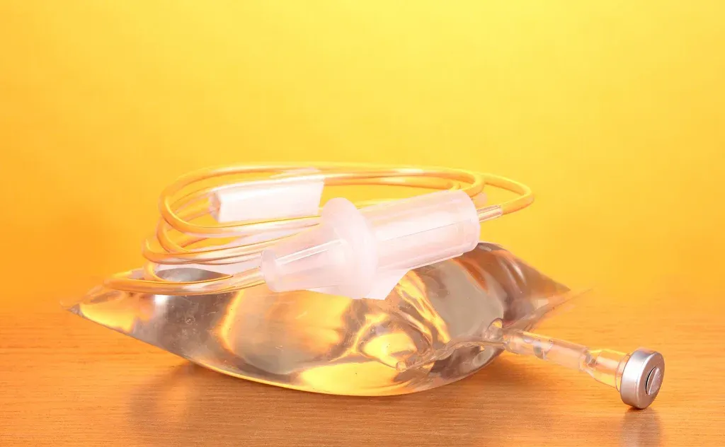 Clear glass oil lamp with amber liquid and a white cotton wick on an orange background