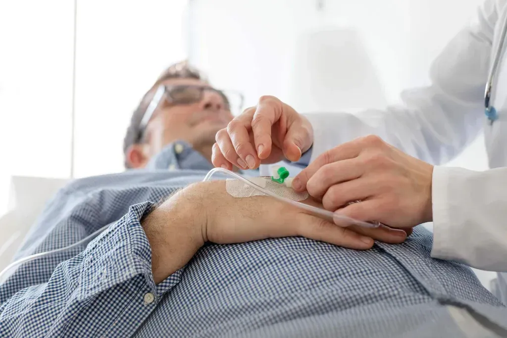 Healthcare worker preparing an IV on a resting patient in a hospital bed