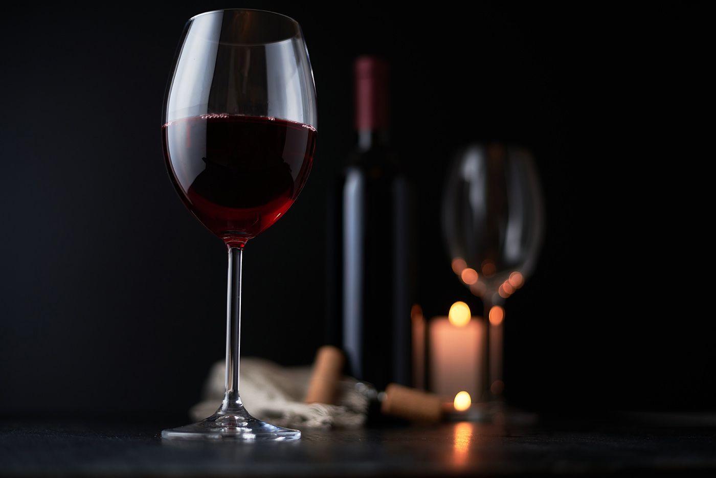 Wine glass and bottle on a dark table with candlelight in the background