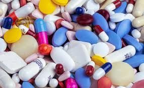 Assorted colorful pills and capsules scattered together on a white surface