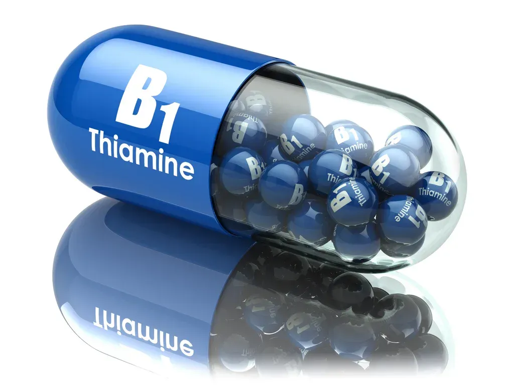 Blue thiamine (B1) capsule filled with blue pills, isolated on white with reflection