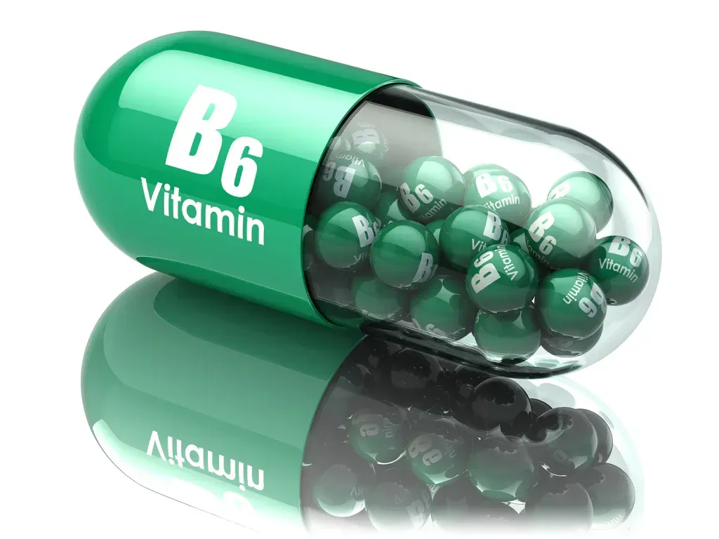 Green vitamin B6 capsules spilling from a transparent pill bottle with reflective surface