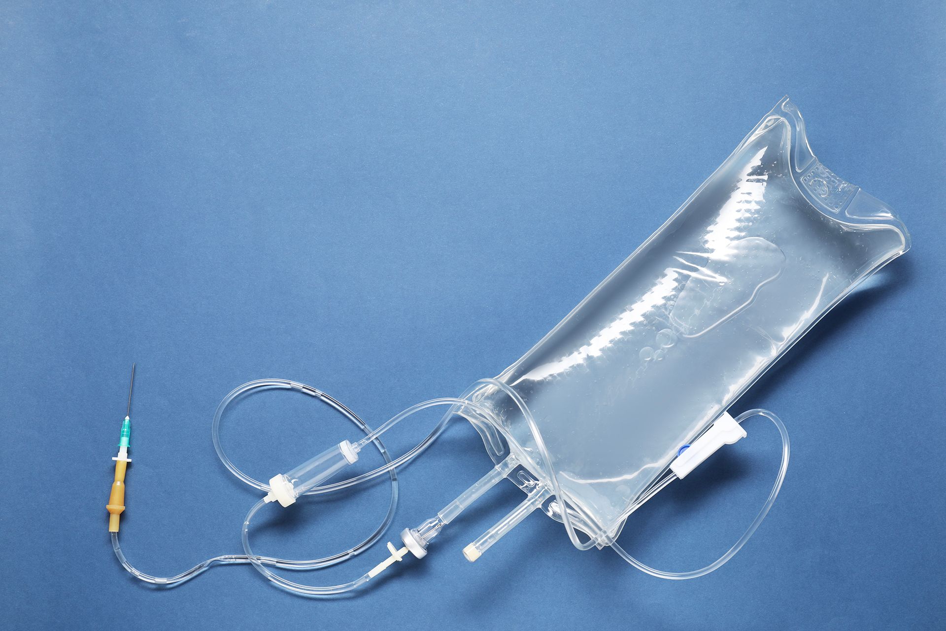 IV bag with attached tubing and connector on a blue background