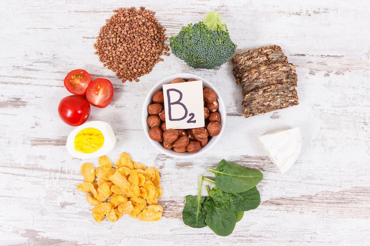 Foods rich in vitamin B2 arranged around a central B2 label on a white wooden background