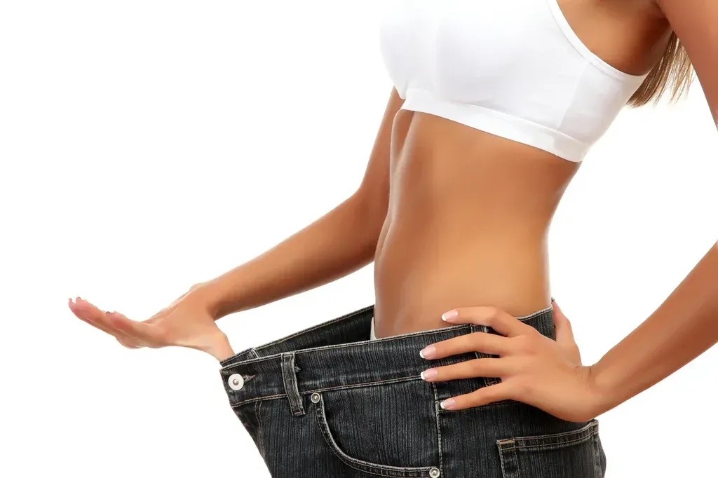 Person pulling up loose jeans against a white background