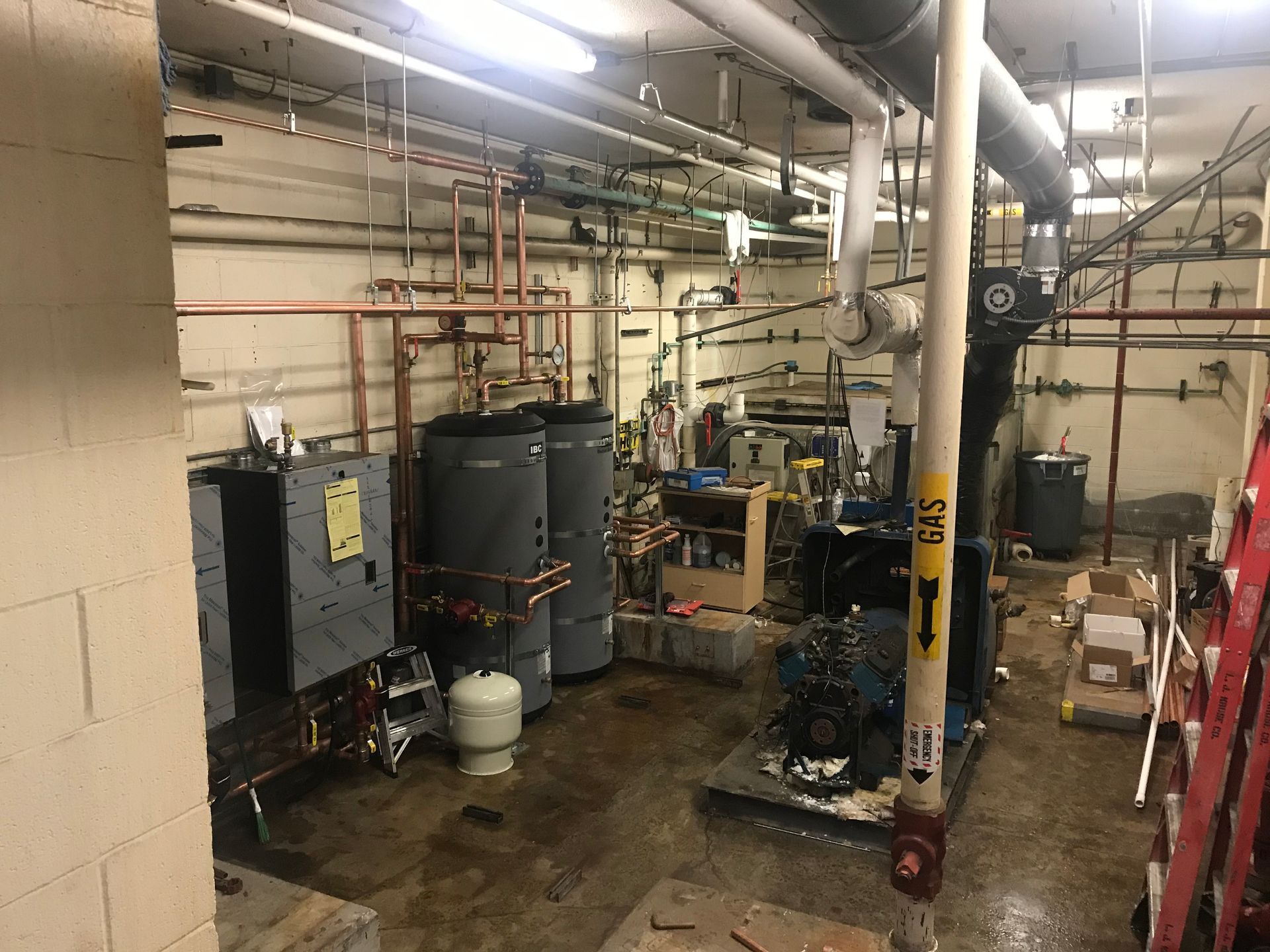 A room with a lot of pipes and a ladder in it